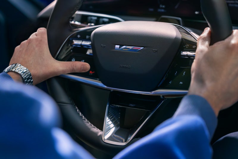 Close-up of a Man About to Press the V-Button on the 2026 OPTIQ-V Steering Wheel | Grubbs Cadillac of Wichita Falls in WICHITA FALLS TX