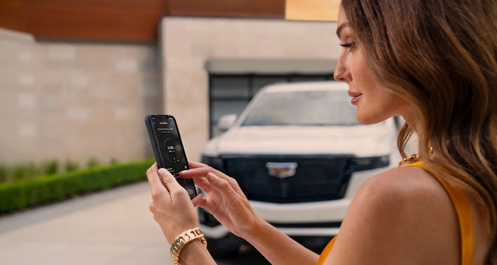 lady checking her mobile with a Cadillac vehicle background | Grubbs Cadillac of Wichita Falls in WICHITA FALLS TX